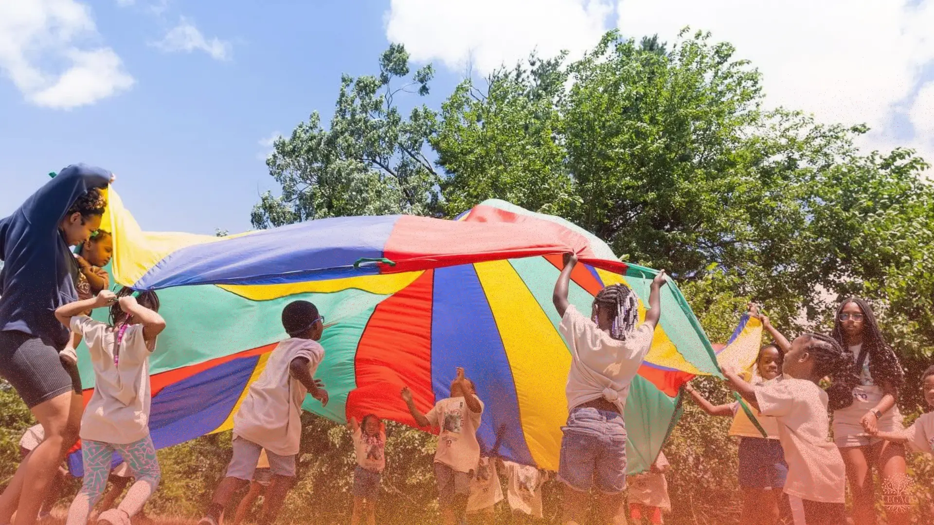 Children and volunteers playing together with a colorful parachute outdoors