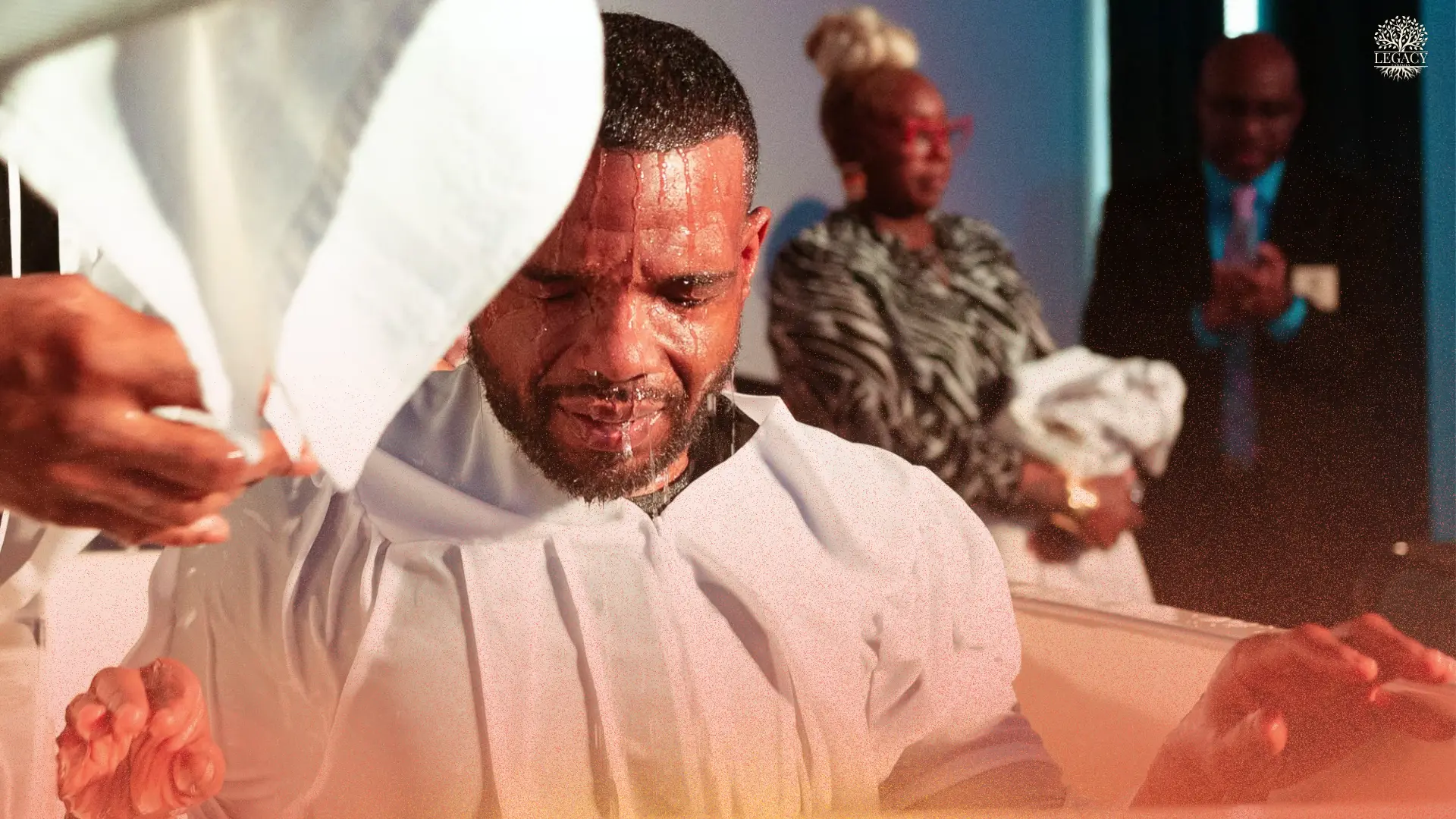 A man emerging from baptism surrounded by the church family